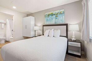 Une chambre d’hôtel avec un grand lit, deux tables de chevet avec des lampes, une armoire et un tableau au mur.