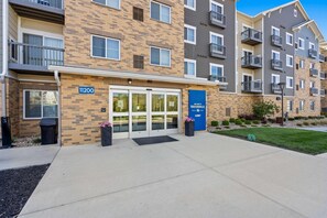 Un edificio de apartamentos de varios pisos con fachada de ladrillo, numerado 11200, que cuenta con una entrada de vidrio y un letrero azul que dice "Welcome to Waterwalk".