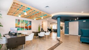 Un área de recepción moderna con techo de madera, mostrador de recepción, sillas blancas y una pared de acento azul.