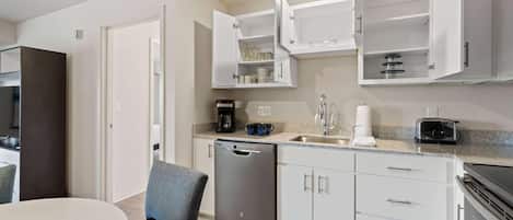 A modern kitchen with white cabinets, a dishwasher, a coffee maker, and a toaster.