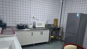 Eine Küche mit weißen Schränken, einer Mikrowelle, einem Kühlschrank und einem Spülbecken.