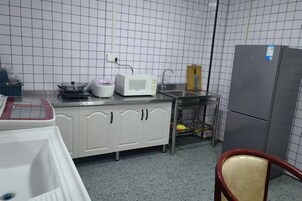 Uma cozinha com armários brancos, micro-ondas, geladeira e pia.
