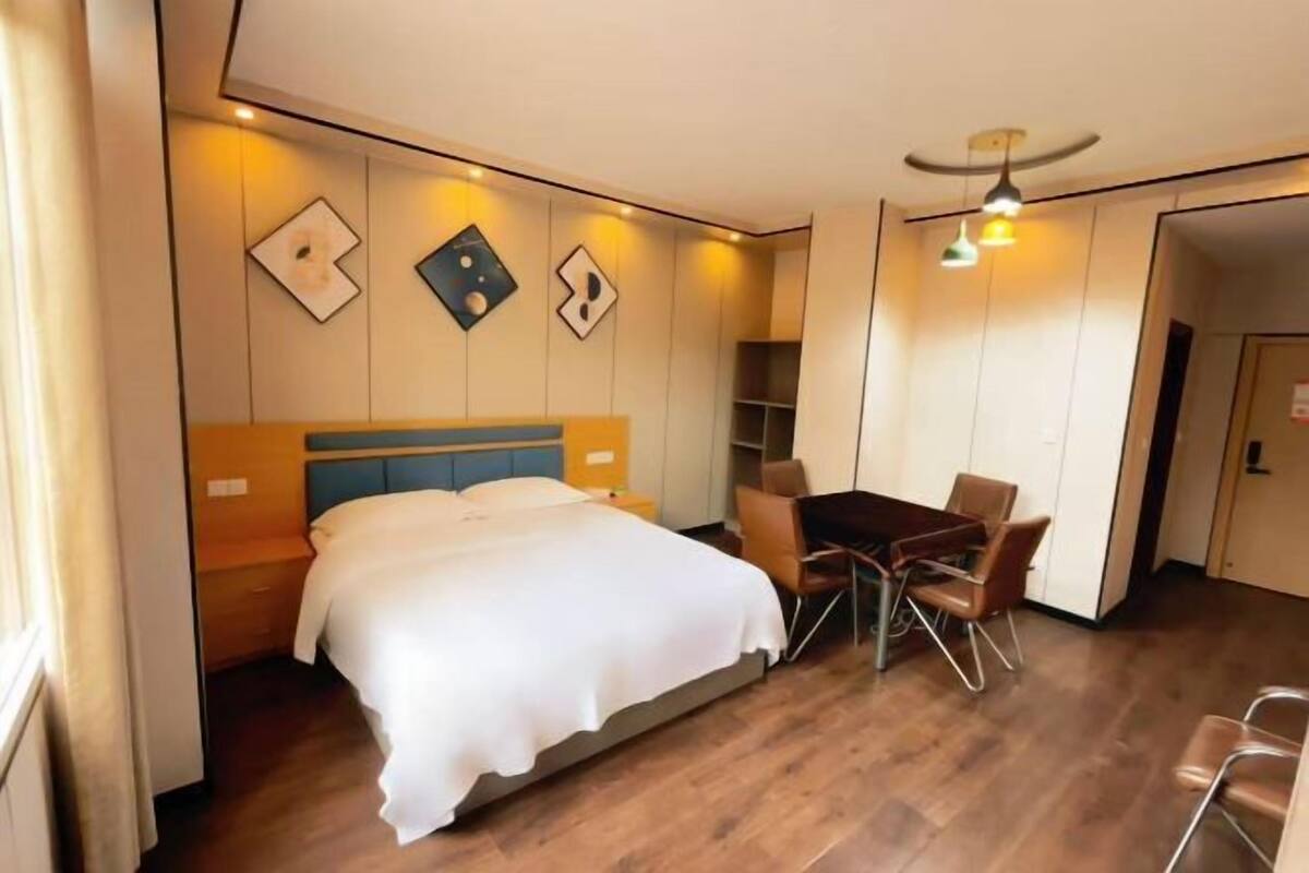 Una habitación de hotel con una cama, una mesa de comedor con sillas y obras de arte colgadas en la pared.