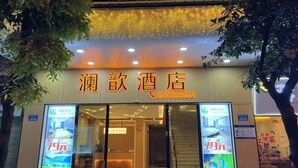 Ein Hotel Eingang mit einem Schild in chinesischen Schriftzeichen und einer Telefonnummer. An den Glastüren befinden sich zwei große Plakate, die einen Preis von 79 Yuan bewerben.