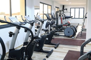 Un gimnasio con varias máquinas de ejercicio, incluyendo cintas de correr y elípticas, dispuestas en filas.