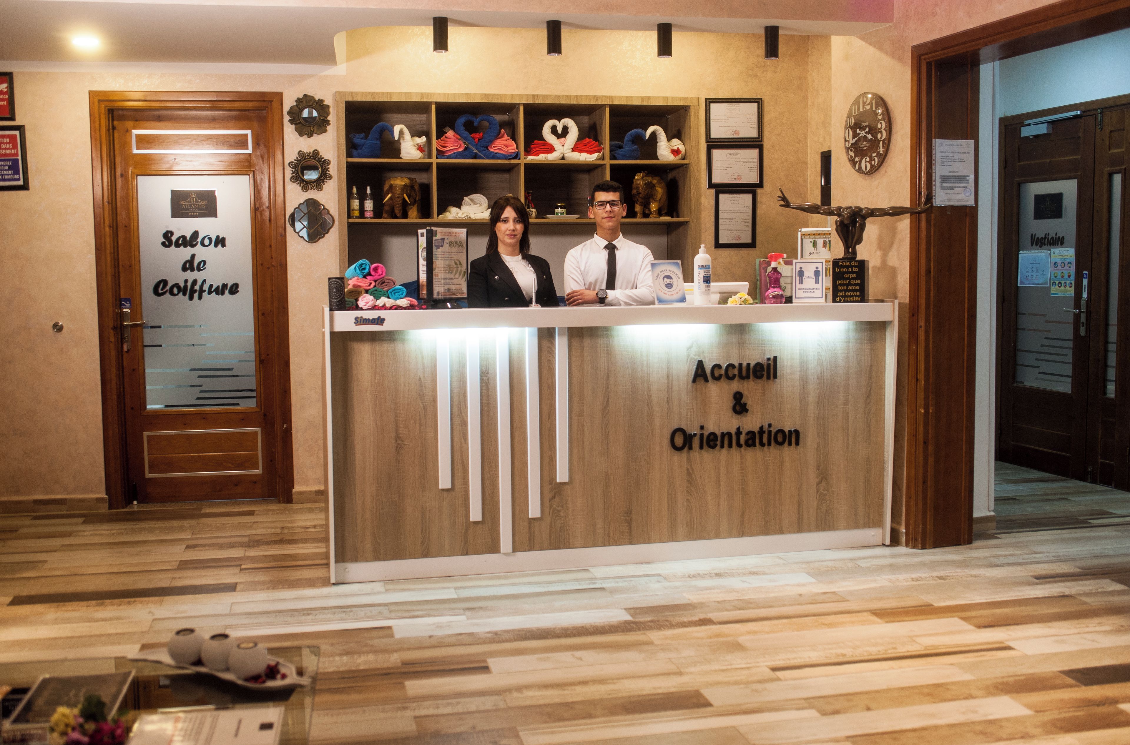 Een receptiebalie met een bord waarop 'Accueil & Orientation' staat, en een houten inrichting.
