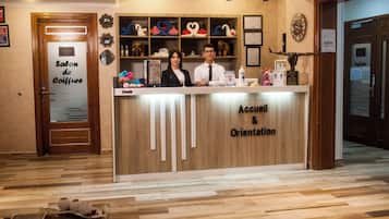 Een receptiebalie met een bord waarop 'Accueil & Orientation' staat, en een houten inrichting.