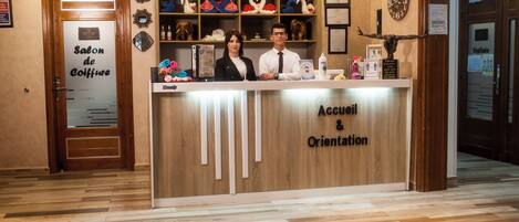 A reception desk with a sign reading 'Accueil & Orientation' and a wooden interior.