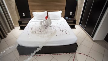 Een hotelkamer met een net opgemaakt bed, een decoratieve zwaan als middelpunt en een kantbiesen rand op de sprei.