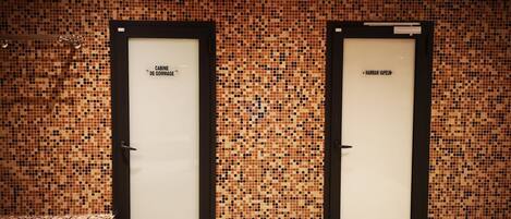 Two doors with labels 'CABINE DE GOMMAGE' and 'HAMMAM VAUPEUR' in a tiled room.