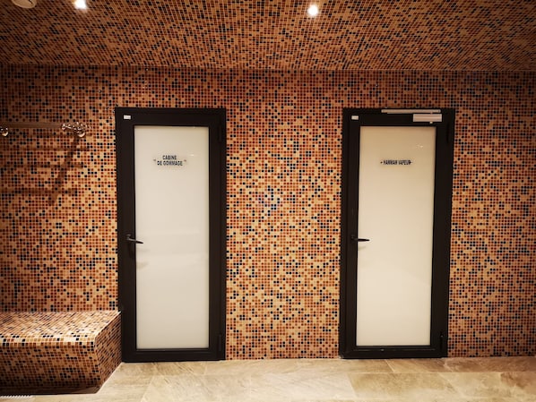 Two doors with labels 'CABINE DE GOMMAGE' and 'HAMMAM VAUPEUR' in a tiled room.