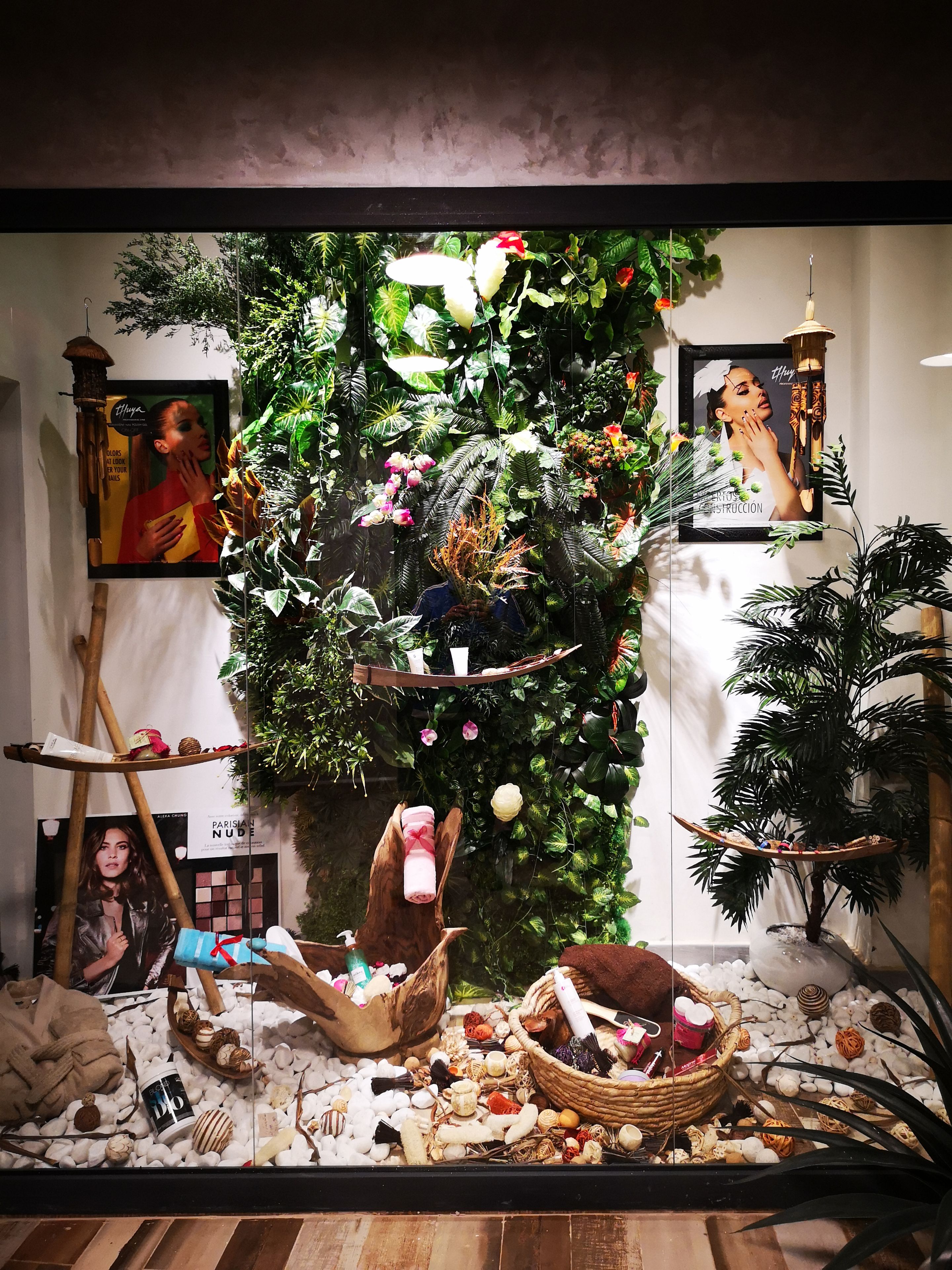 Una exhibición con diversos objetos, como un cuadro enmarco, una lámpara colgante y una pared decorada con plantas.