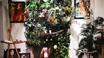 Una exhibición con diversos objetos, como un cuadro enmarco, una lámpara colgante y una pared decorada con plantas.