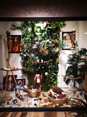 A display with a variety of items including a framed picture, a hanging light fixture, and a wall adorned with plants. - Atlantis Akbou (Béjaïa)
