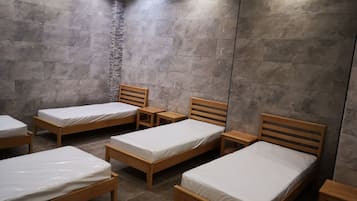 A room with six wooden beds arranged in two rows, each with a wooden nightstand.
