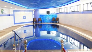 En swimmingpool med blåt loft, liggestole og fliserede vægge.