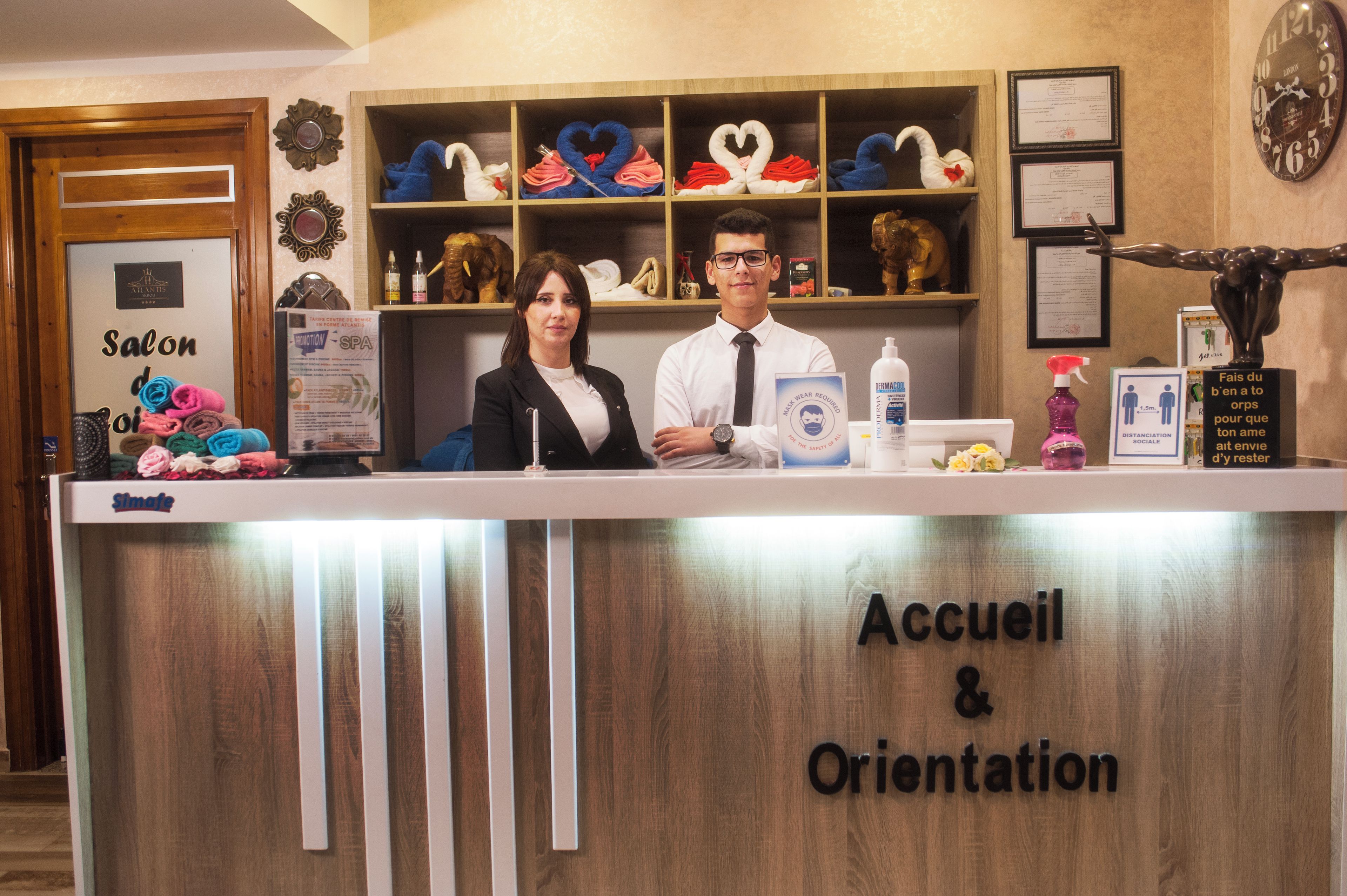 Una reception con un cartello che riporta 'Accueil & Orientation' e un espositore con asciugamani a forma di cuore.