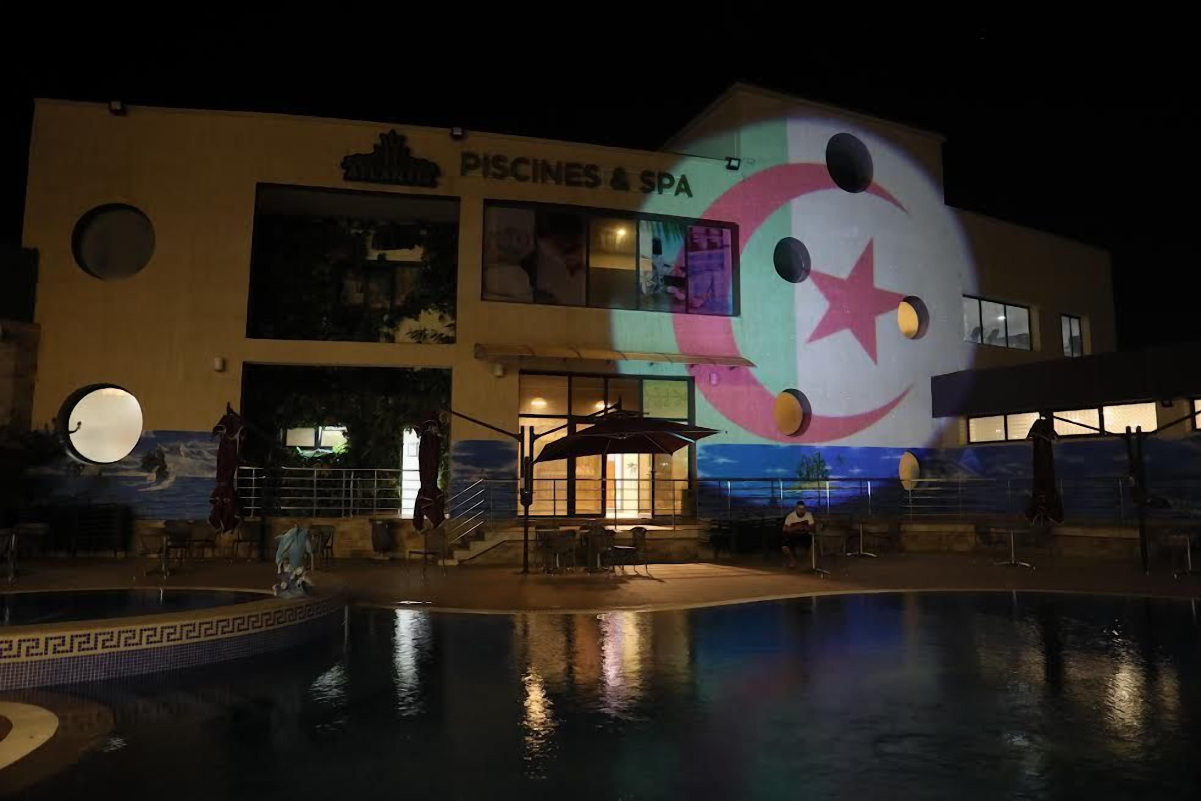 A building with a sign for 'PISCINES & SPA' and a pool area with a mural.