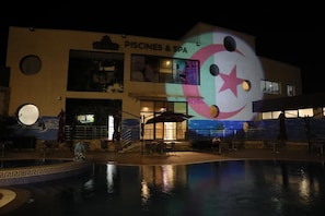Un edificio con un cartel que dice 'PISCINES & SPA' y una zona de piscina con un mural.