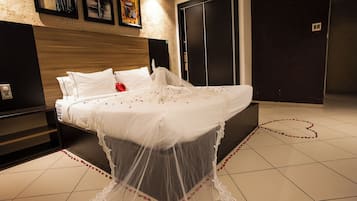 Cama bem arrumada com dossel, mesa de cabeceira e tomada na parede.