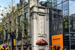 Ein Gebäude mit klassischer Architektur, einer modernen Glasfassade und einem Schaufenster mit einer markanten orangenen Beschilderung.