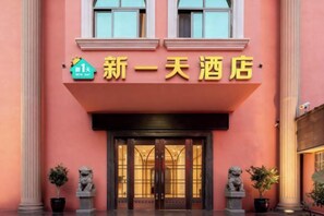 A hotel entrance with a prominent sign, a double door, and two statues flanking the entrance. - Xinyitian Hotel (Wenzhou Xueshan Road Wuma Street Branch) (Wenzhou)