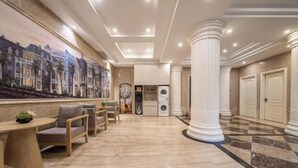 A hotel lobby with a mural, seating area, columns, and a laundry room. - Xinyitian Hotel (Wenzhou Xueshan Road Wuma Street Branch) (Wenzhou)