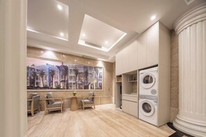 A modern interior with a dining area, a large painting, and a built-in washer and dryer. - Xinyitian Hotel (Wenzhou Xueshan Road Wuma Street Branch) (Wenzhou)