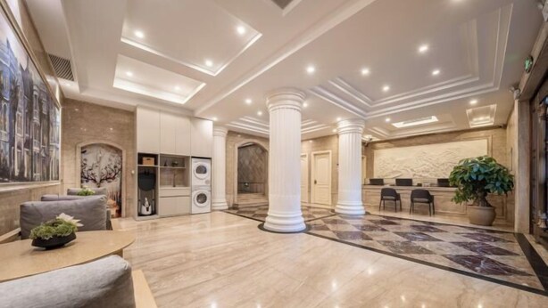 A spacious lobby with a marble floor, a reception desk, and a large column. - Xinyitian Hotel (Wenzhou Xueshan Road Wuma Street Branch) (Wenzhou)