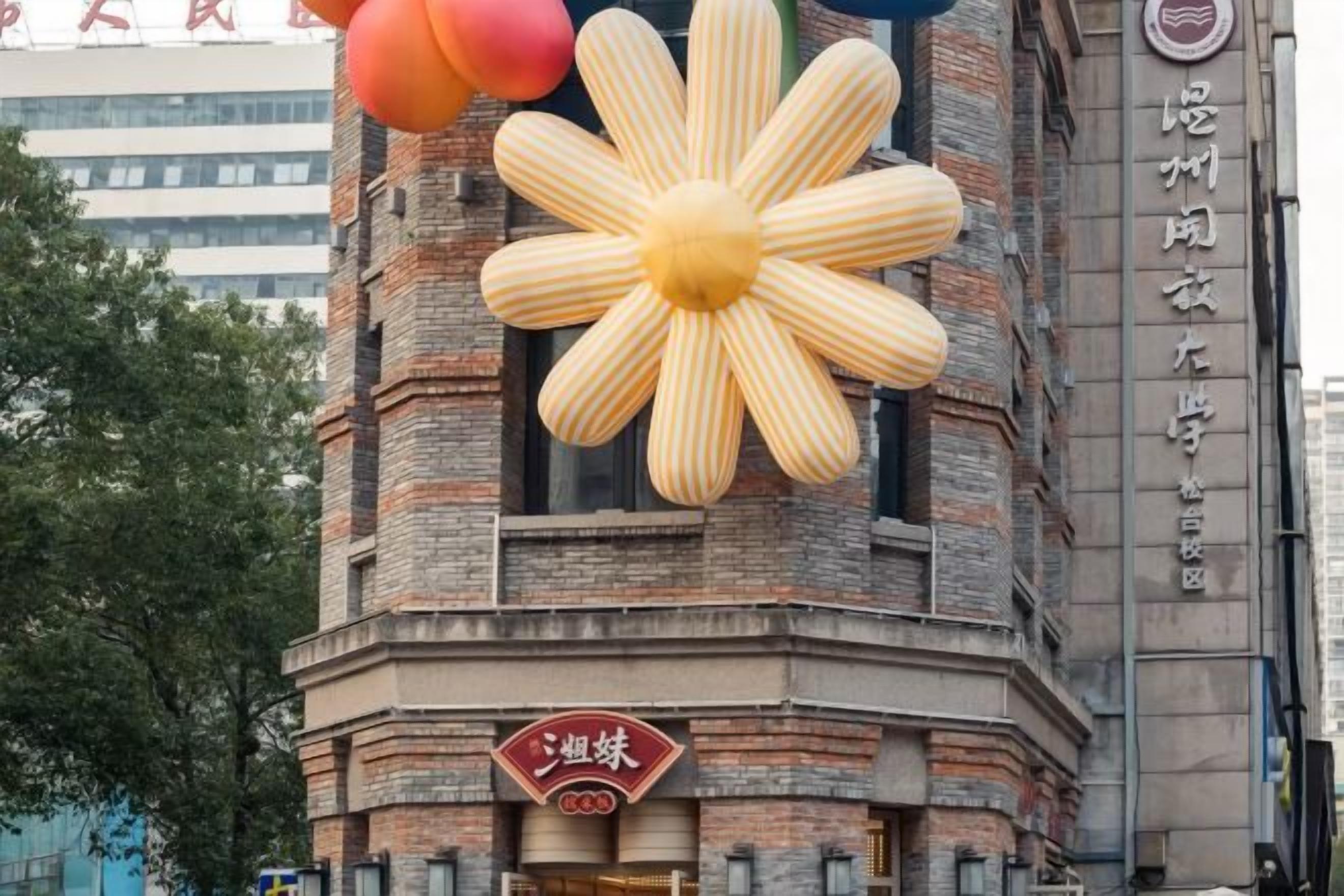 Un edificio con una gran decoración floral en la fachada, un letrero con caracteres chinos y otro más pequeño debajo.