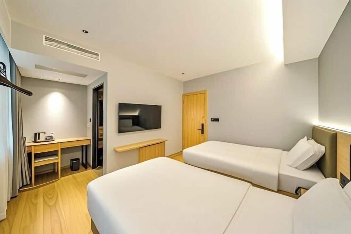 Una habitación de hotel con cama, escritorio, televisor y armario.