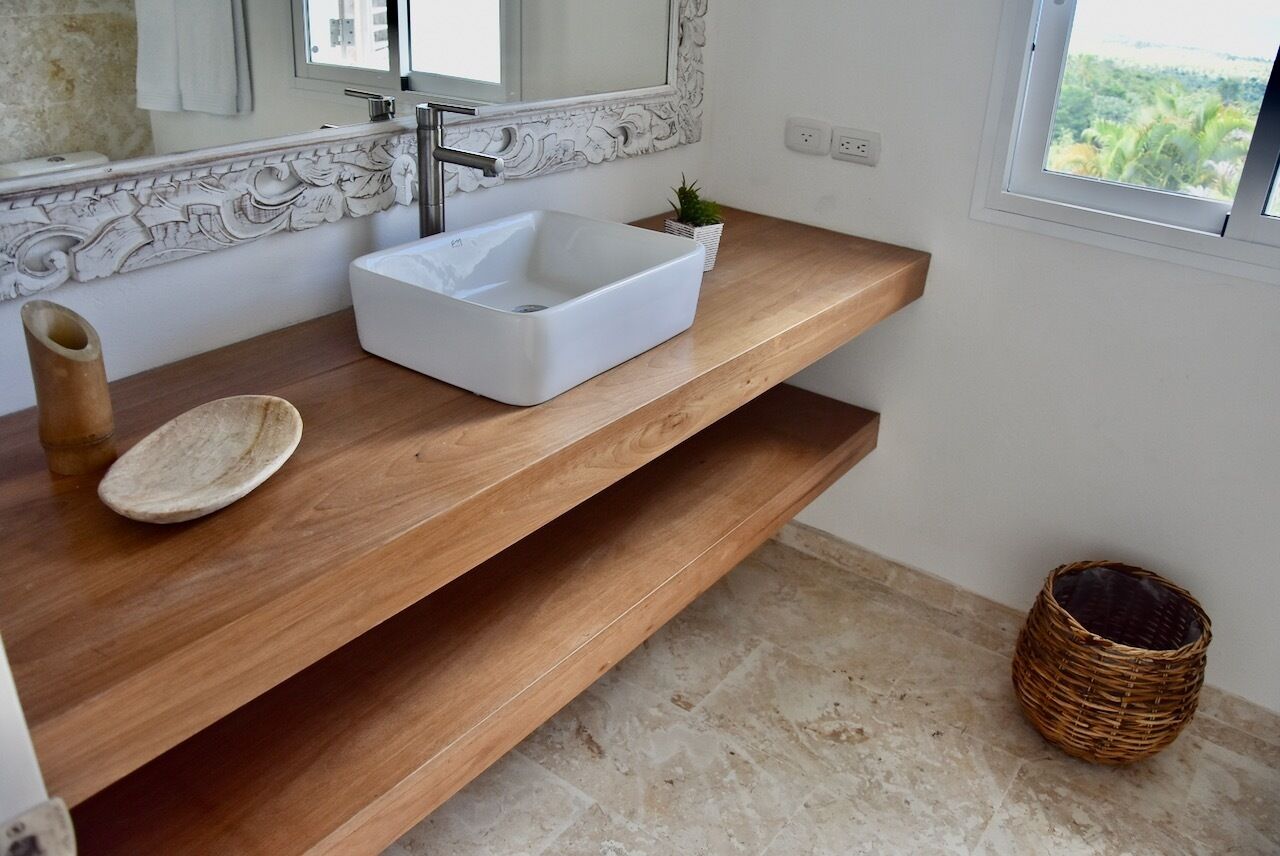 Une salle de bain avec un lavabo blanc, un meuble-lavabo en bois et un miroir décoratif.