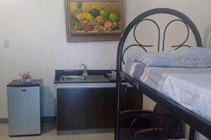 Una habitación pequeña con literas, un kitchenette y un lavamanos.