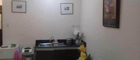 A kitchen with a sink, stove, and cabinets. There are framed pictures on the wall and a vase with flowers on the counter.
