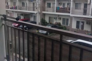 Un edificio residenziale con diversi balconi, alcuni dei quali con panni stesi, e auto parcheggiate lungo la strada.
