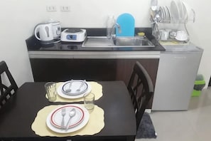 A compact kitchen with a sink, a kettle, a toaster, and a dishwasher. - Kassel Residences Staycation near NAIA (Paranaque)