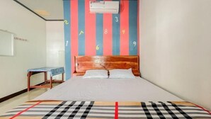 Habitación de hotel con una cama, cabecera de madera, aire acondicionado de pared y una mesita con mantel azul.