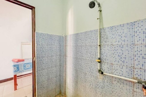 A bathroom with a shower, tiled walls, and a visible pipe. - Ekas Beach Guesthouse Mitra RedDoorz (Lombok)