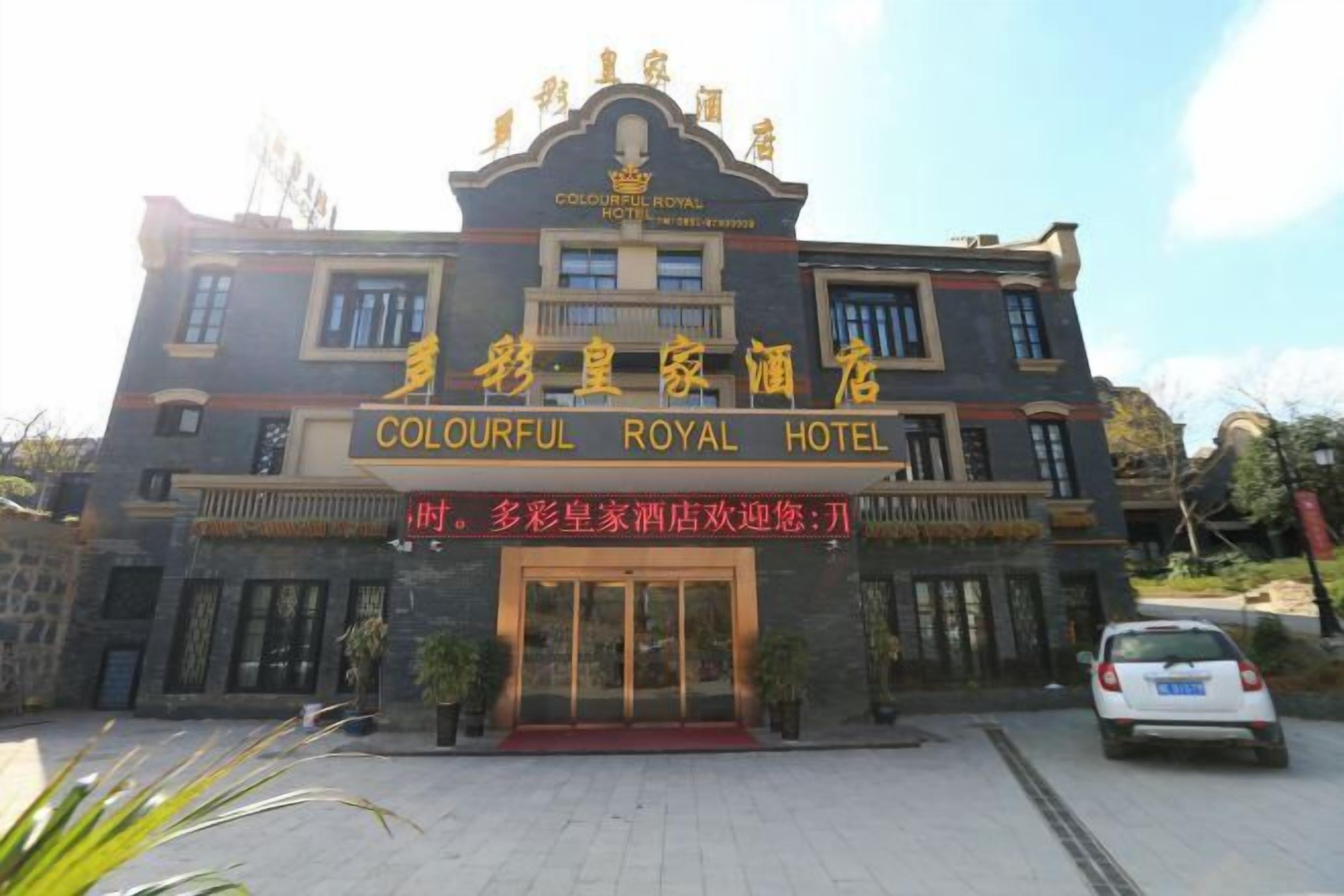The entrance of the Colourful Royal Hotel with a prominent sign and a red carpet leading to the doors.
