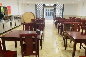 A dining area with multiple tables and chairs, a buffet counter, and a large round table in the center. - Colorful Royal Hotel (Qingzhen Time Guizhou Ancient Town) (Qingzhen)