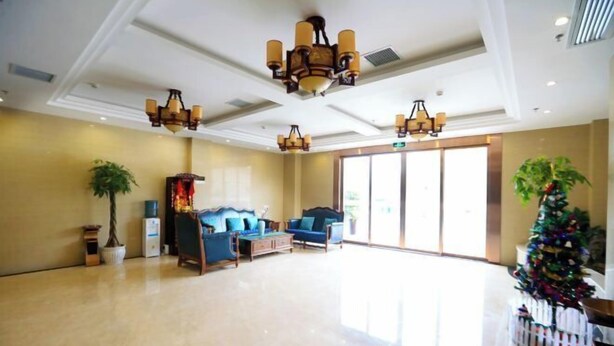 A spacious lobby with a high ceiling, chandeliers, a large plant, a Christmas tree, and a seating area with blue sofas. - Colorful Royal Hotel (Qingzhen Time Guizhou Ancient Town) (Qingzhen)