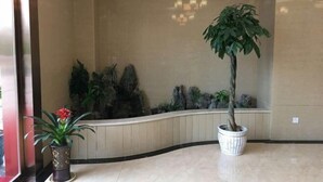 A lobby with a curved bench, a potted plant, and a wall with a rock garden. - Colorful Royal Hotel (Qingzhen Time Guizhou Ancient Town) (Qingzhen)