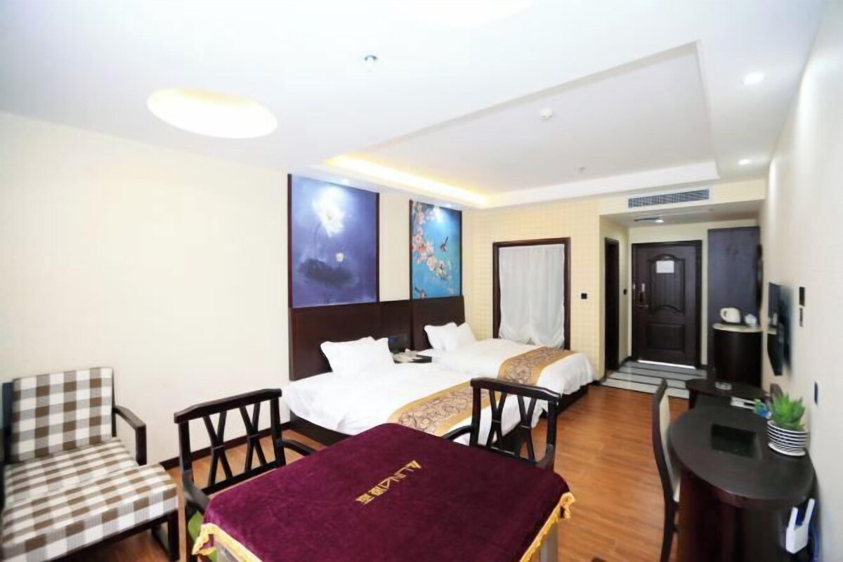 A hotel room with two beds, a desk, a chair, and a television.