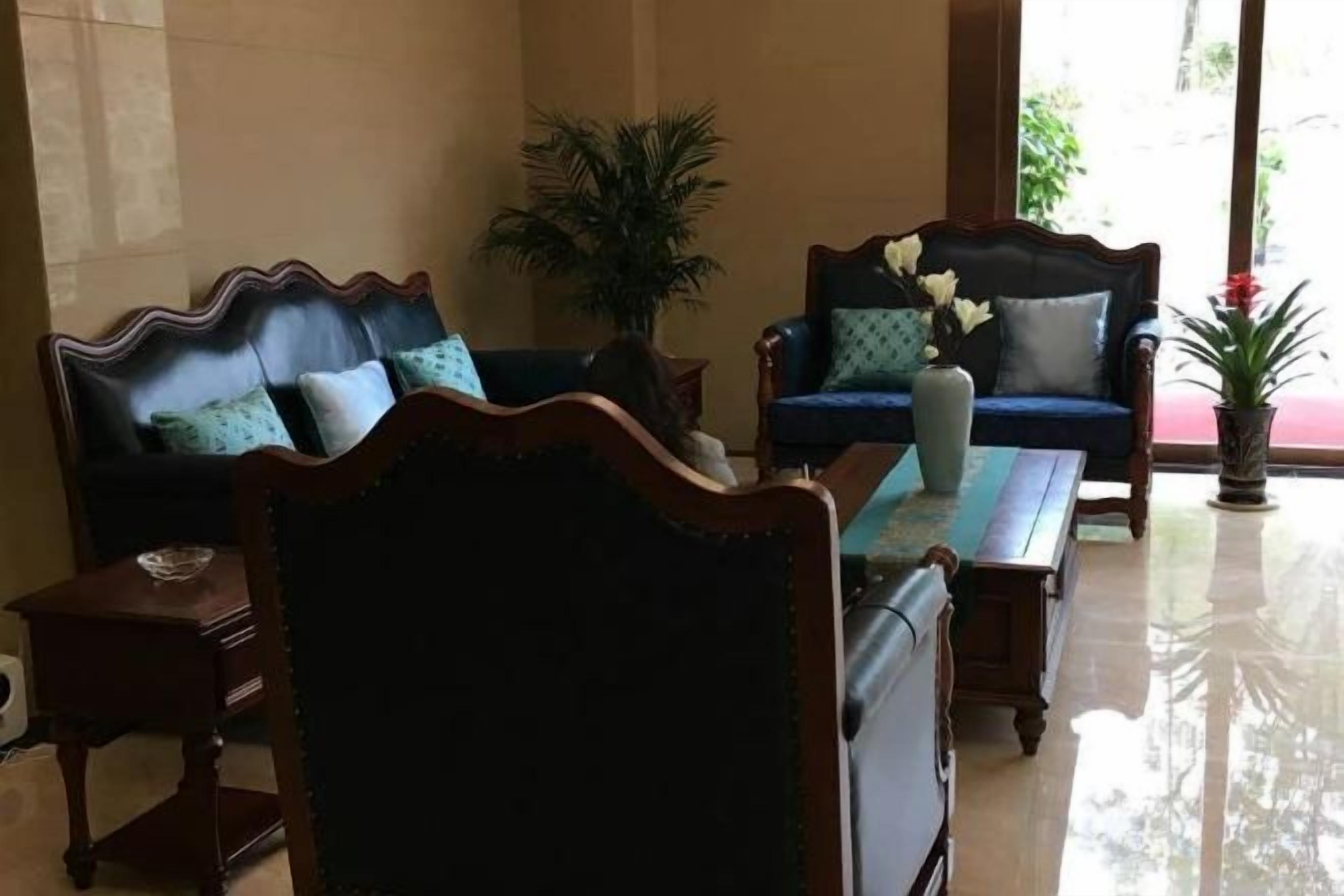 Quarto com sofá, cadeira, mesa e planta em vaso.
