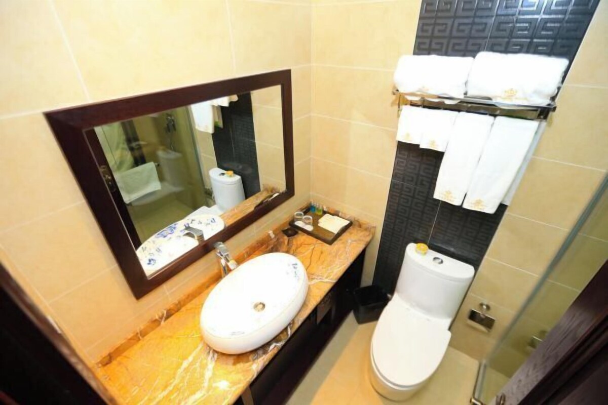 A bathroom with a marble sink, a mirror, a toilet, and a glass shower enclosure.