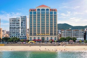 A hotel with multiple floors, a beach in the foreground, and a mountainous backdrop. - Century Seaview Hotel (Nan'ao County)