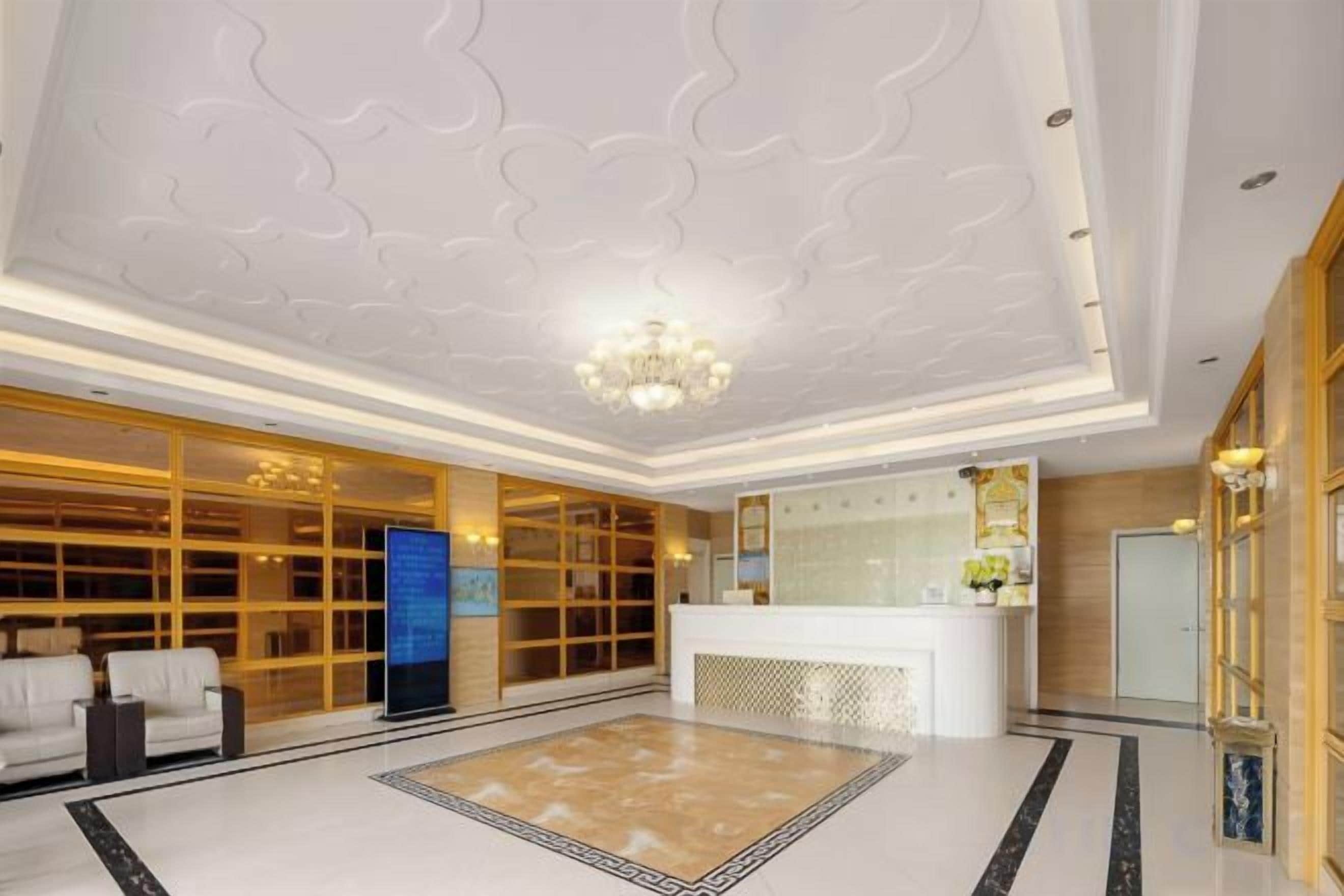 A hotel lobby with a reception desk, seating area, and a decorative ceiling.