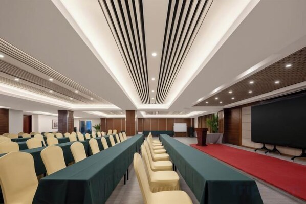 A conference room with rows of tables and chairs, a large screen, and a red carpet. - Century Seaview Hotel (Nan'ao County)