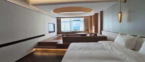 Une chambre d’hôtel moderne dotée d’un grand lit, d’un coin salon avec vue et d’une télévision.