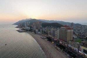A coastal cityscape with a beach, high-rise buildings, and a mountain in the background. - Century Seaview Hotel (Nan'ao County)